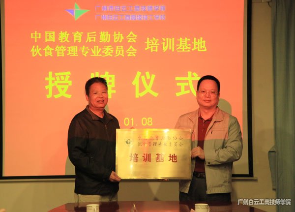 中國教育后勤協(xié)會伙食管理專業(yè)委員會副主任王淼光（左）向李孟強院長（右）授牌